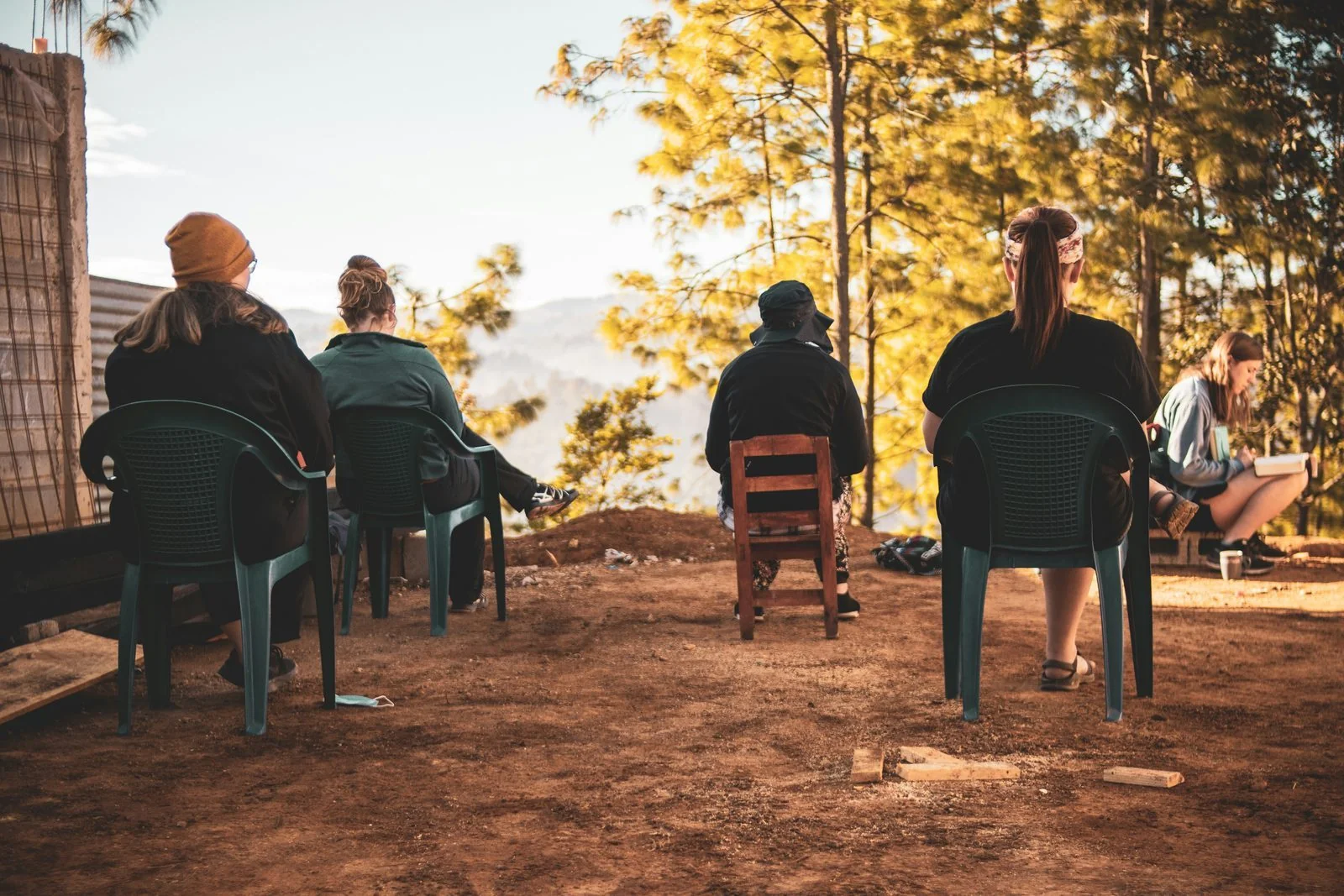 Small group seated in chairs at a hillside lookout, in a quiet shared moment.