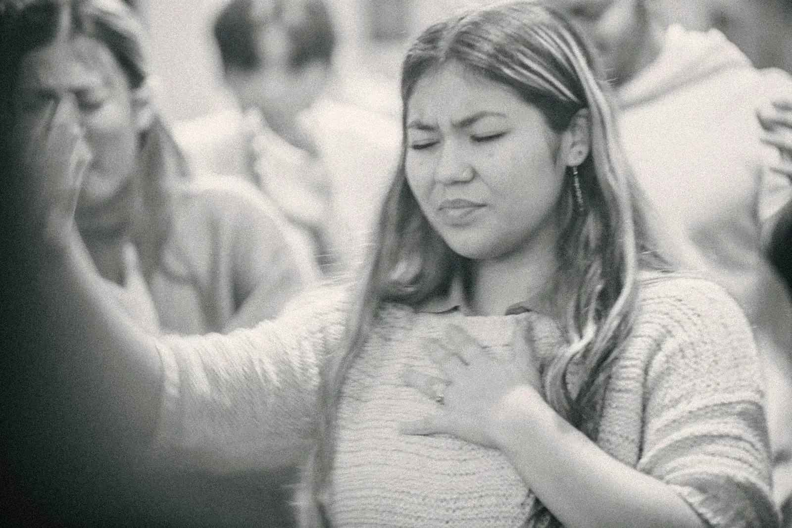 Person with eyes closed and a hand on the chest, settling in a quiet moment.