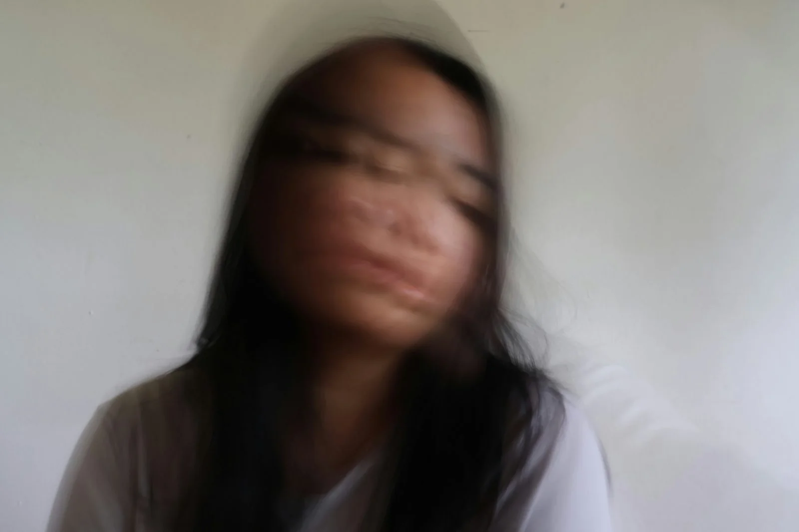 A figure in soft motion against a pale wall, blurred and free.