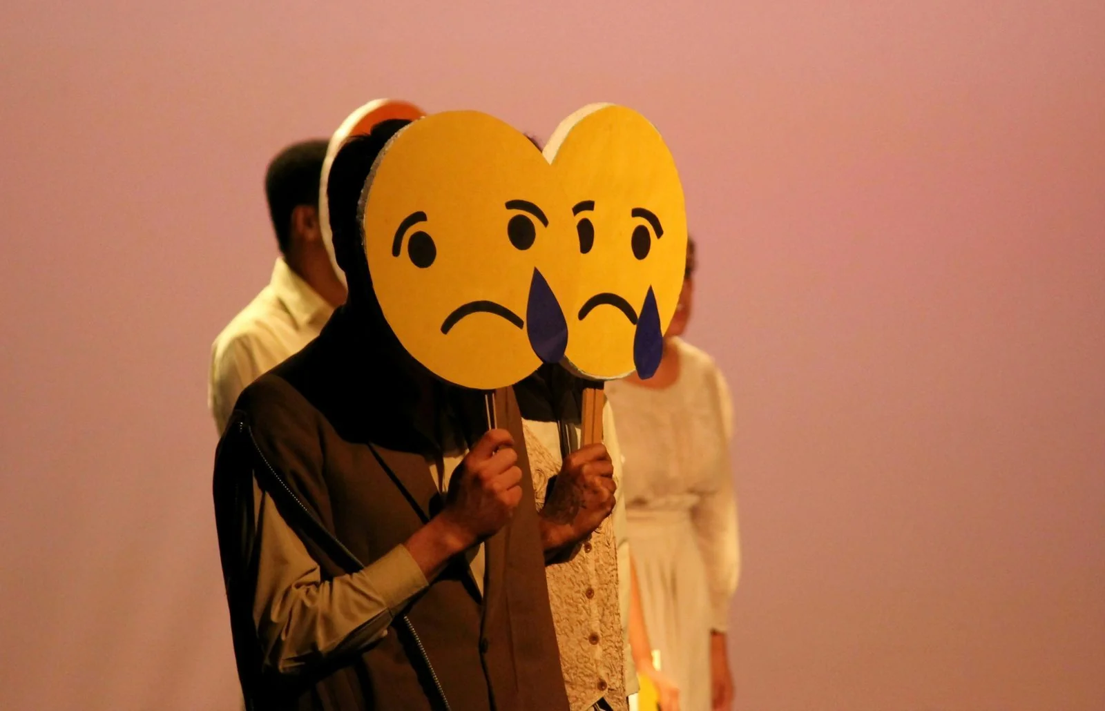 Performers holding cartoon masks during a drama therapy exercise.