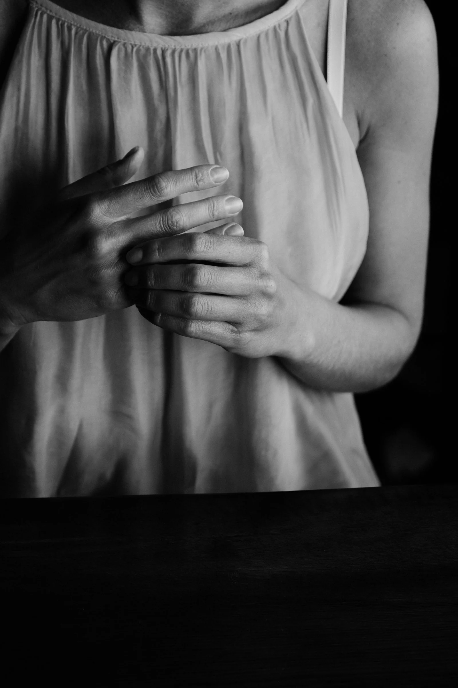 Person with hands resting over the chest in a grounded posture.