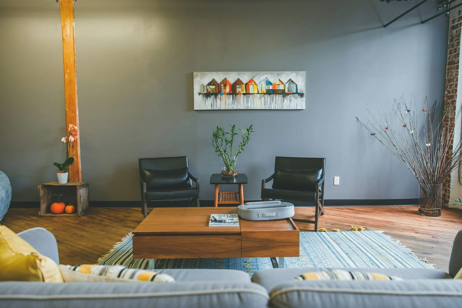 A warm consultation room with two black leather chairs, a small side table, and abstract art on the wall.
