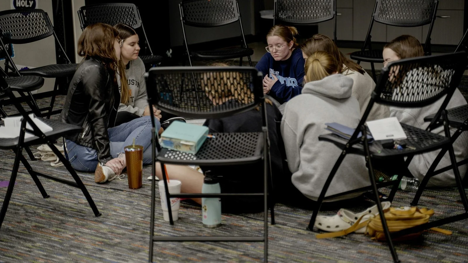 Students gathered in a circle on the floor in a workshop setting.